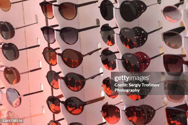 sunglasses for sale in store outdoors - getönte sonnenbrille stock-fotos und bilder