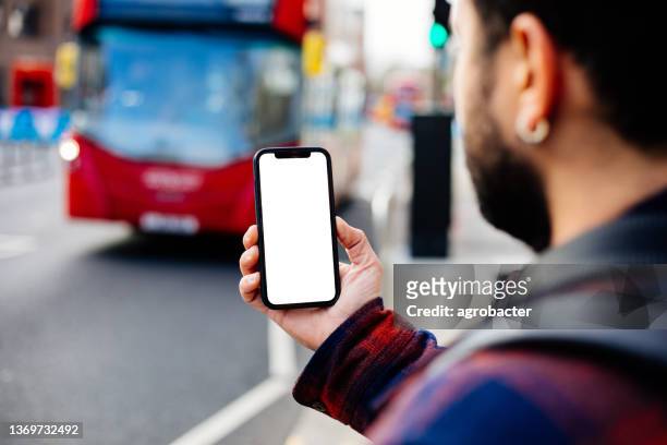 young man using phone on the street in london - london buses stock pictures, royalty-free photos & images