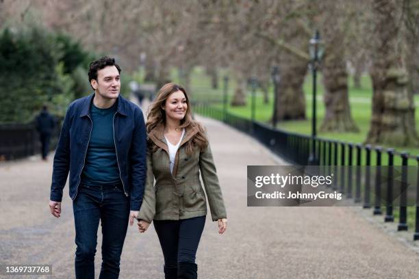 early 30s man and late 20s woman walking through london park - man talking to camera stock pictures, royalty-free photos & images