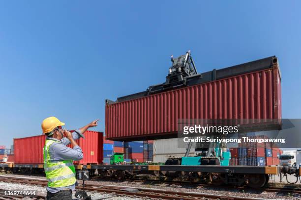 young man engineer working at container cargo warehouse for quality control, import export shipping or train freight transportation. - boxcar stock-fotos und bilder