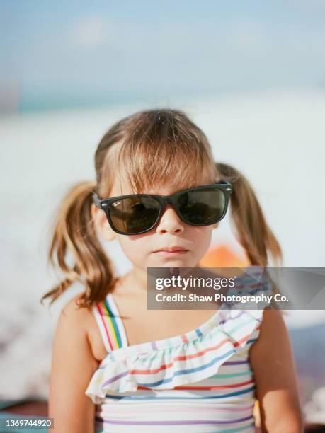 little girl in pigtails with serious face wearing sunglasses and a bathing suit - naples florida stock-fotos und bilder