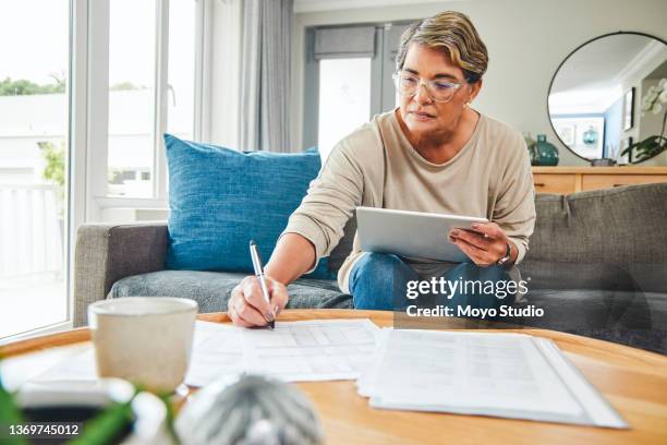 shot of a mature woman using a digital tablet while going through paperwork at home - the cast of will grace visits the tonight show starring jimmy fallon stockfoto's en -beelden