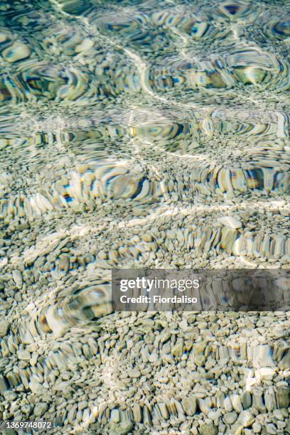 sea pebble bottom showing through crystal clear blue water - lowest stockfoto's en -beelden