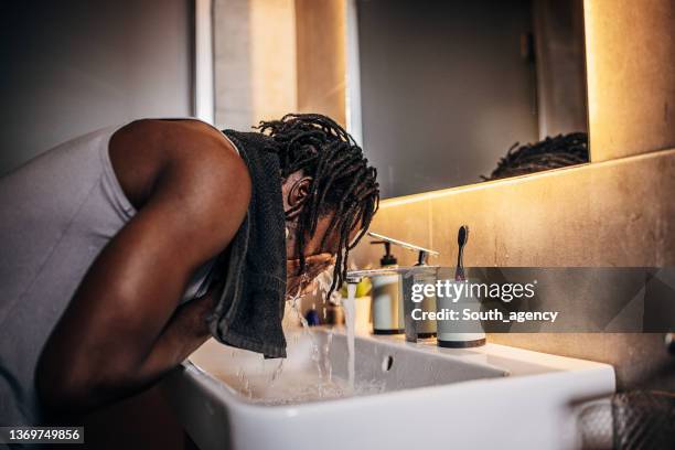mann waschen gesicht im badezimmer - gesichtsreinigung stock-fotos und bilder