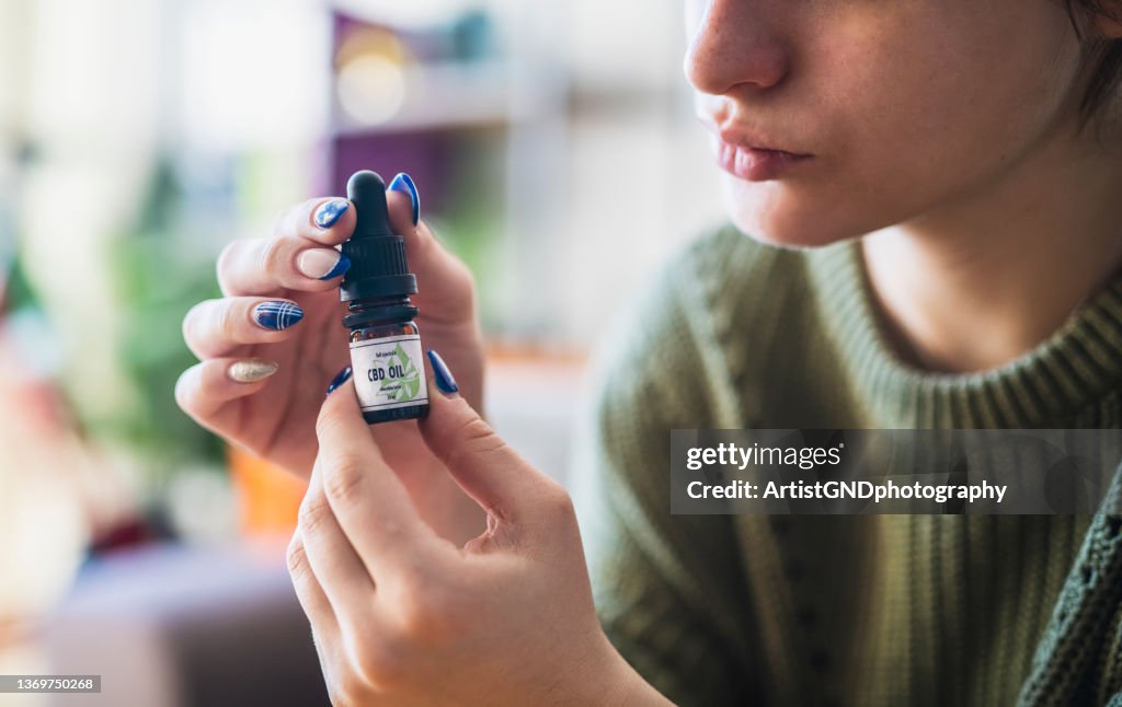 Woman holding CBD oil container.