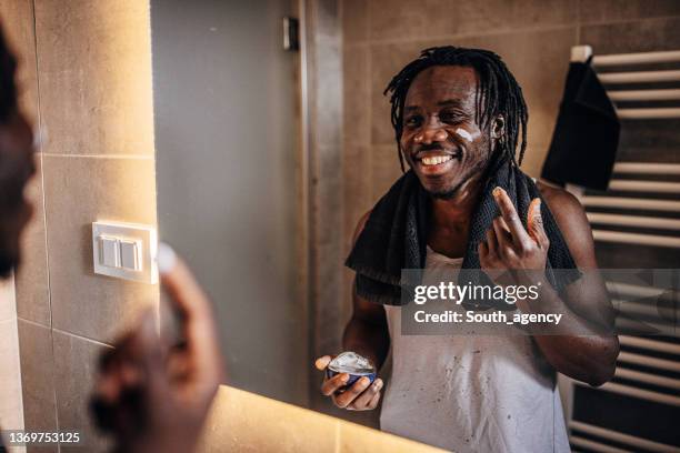 hombre aplicando crema hidratante - hombre crema facial fotografías e imágenes de stock