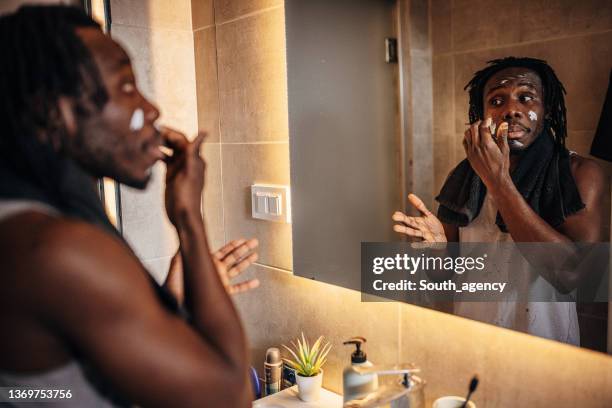 man applying moisturizer cream - man applying moisturizer stock pictures, royalty-free photos & images