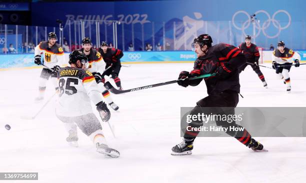 Jordan Weal of Team Canada hits a shot in front of Marcel Brandt of Team Germany during the first period of the Men's Ice Hockey Preliminary Round...