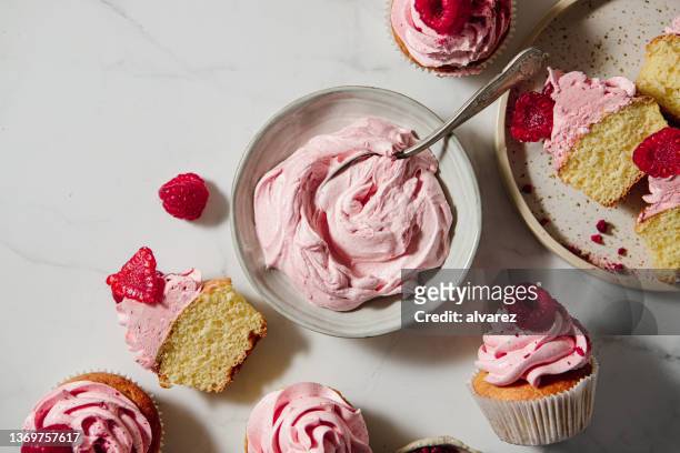 pink whipped cream in a bowl with half sliced raspberry cupcakes on table - cake bowl stock pictures, royalty-free photos & images