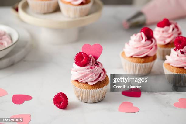 frisch zubereitete himbeer-cupcakes auf der küchentheke - kuchen und süßwaren stock-fotos und bilder