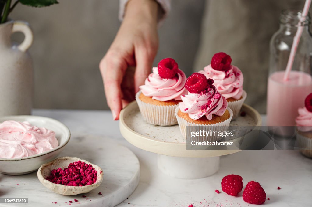 Primer plano de mujer con deliciosos cupcakes de frambuesa en la cocina
