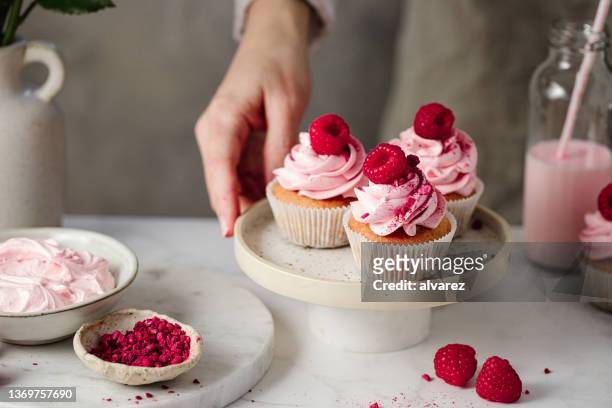 close-up of woman with delicious raspberry cupcakes in kitchen - woman cooking dessert bildbanksfoton och bilder