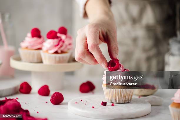 woman preparing delicious raspberry cupcakes - pastry chef stock pictures, royalty-free photos & images