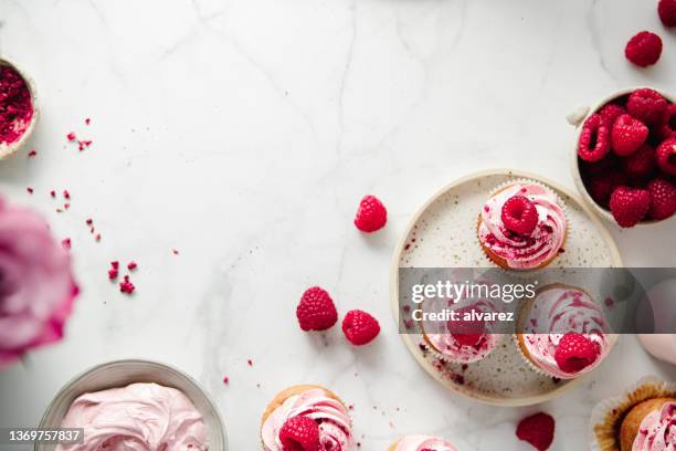 freshly prepared raspberry cupcakes on kitchen counter - toetje stockfoto's en -beelden