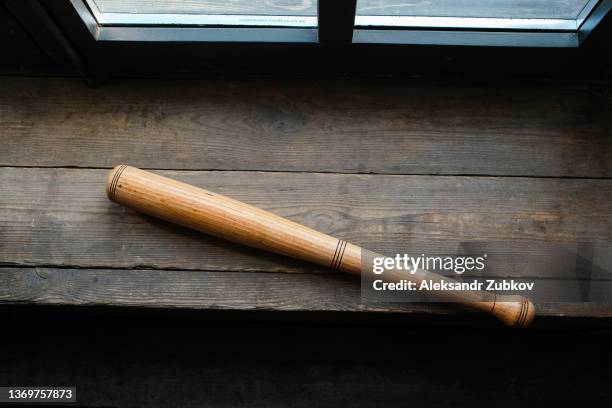 a wooden baseball bat is lying on a table or windowsill. the concept of sports play and leisure, entertainment and competitions, self-defense, defense and protection. - bate de béisbol fotografías e imágenes de stock