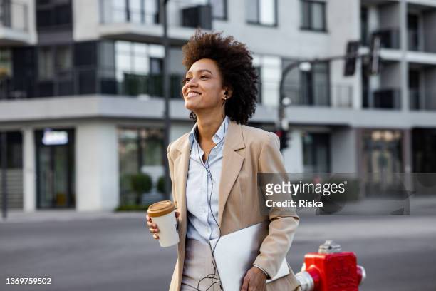gut gekleidete frau, die nach der arbeit auf der straße geht - professional woman coffee stock-fotos und bilder