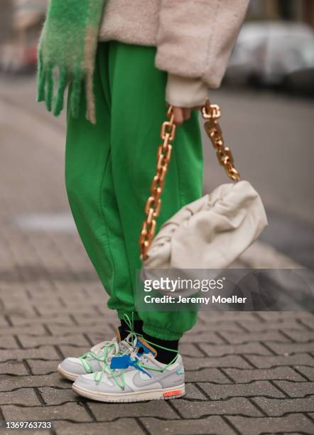 Sonia Lyson is wearing Nike x Off White beige sneaker, Zara green joggingpants, H&M teddy jacket and Bottega Veneta beige pouch on February 09, 2022...