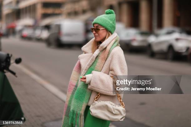 Sonia Lyson is wearing Nike x Off White beige sneaker, Zara green joggingpants, COS green hat, COS knit sweater, and colorful COS scarf, Glambou...