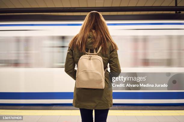 woman with backpack standing on platform in underground - metro platform stockfoto's en -beelden