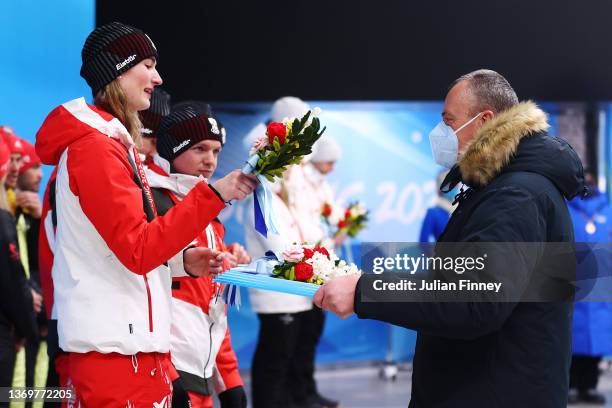 Einars Fogelis, FIL President , presents flowers to silver medallists Team Austria during the medal ceremony for the Luge Team Relay on day six of...