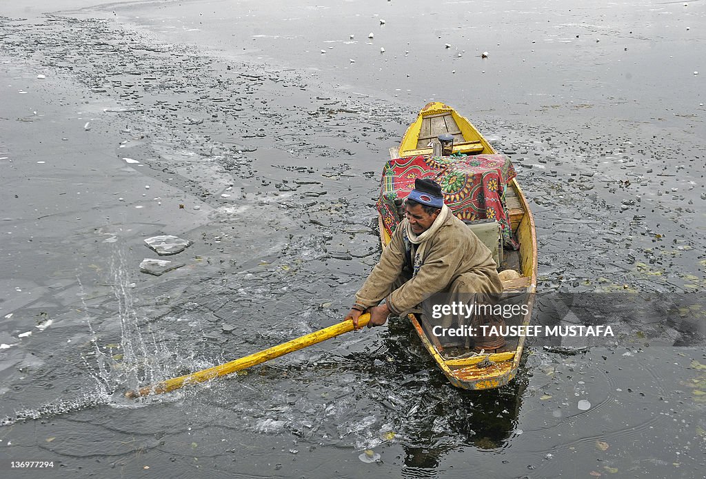 Kashmiri boatman breaks the frozen ice t