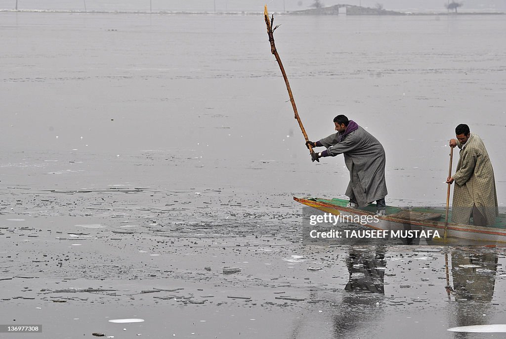 Kashmiri boatman breaks the frozen ice t