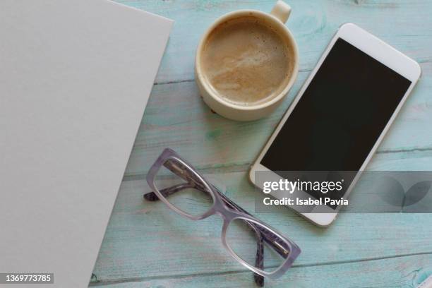 flat lay of book, eyeglasses, smartphone and coffee cup on desk - phone cover stockfoto's en -beelden