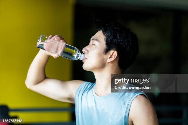 young athletic man drinking water in gym. - lap body area fotografías e imágenes de stock