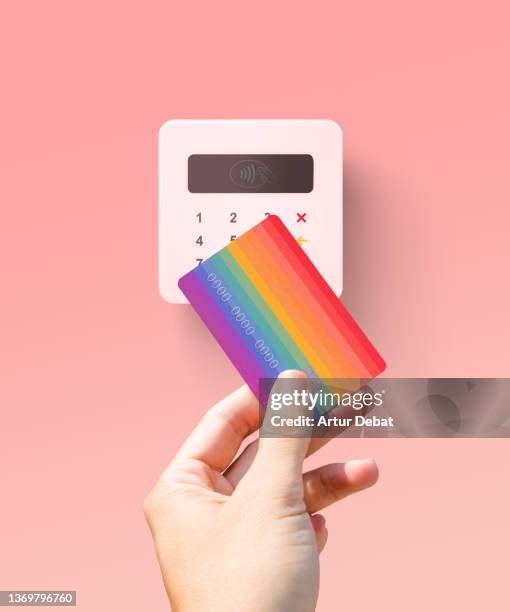 paying to wireless point of sale (pos) (pop) reader using colorful rainbow credit card. - store studios ストックフォトと画像