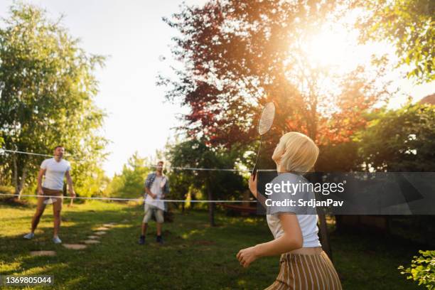 carefree friends playing badminton, during summer day in the garden - backyard games stockfoto's en -beelden