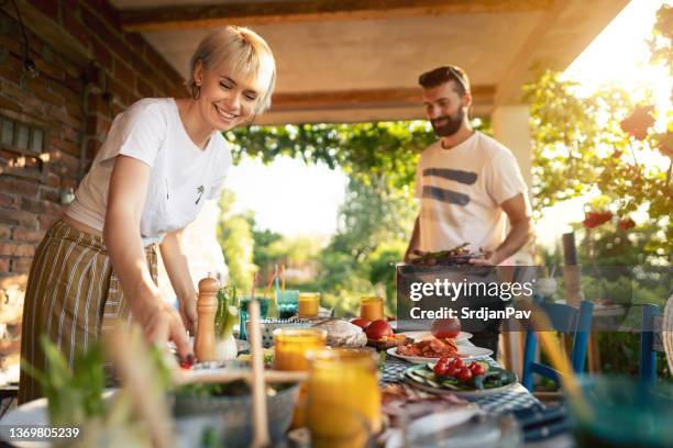 fröhliche freunde bereiten essen für das bbq-treffen im garten zu - barbecue stock-fotos und bilder