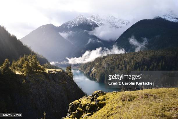 view of diablo lake with sunshine, clouds and snowy mountain peaks - oregon wilderness stock pictures, royalty-free photos & images