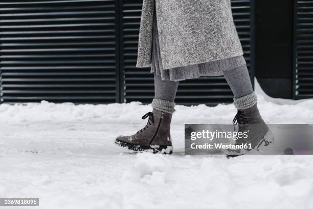 woman wearing snow boots walking on footpath - woman boots fotografías e imágenes de stock