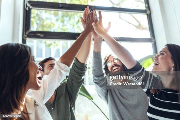 cheerful multiracial businessmen and businesswomen high-fiving in coworking office - dammi un cinque foto e immagini stock