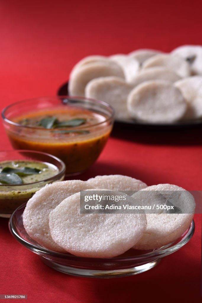 Idli with Sambar and coconut chutney on red background