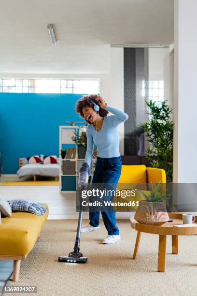 cheerful young woman enjoying music and cleaning carpet in living room - spring clean and female stock pictures, royalty-free photos & images