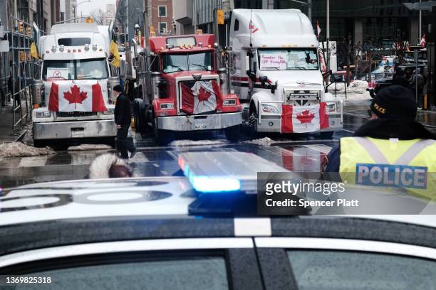 People walk near Canadian Parliament buildings as hundreds of truck drivers and their supporters gather to block the streets of downtown Ottawa as...