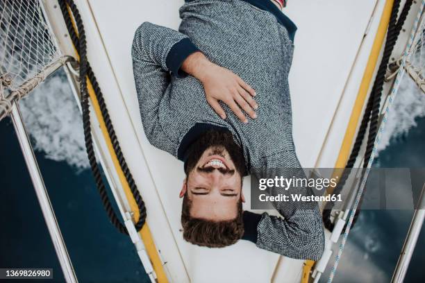 smiling young man lying on sailboat - hands behind head stock pictures, royalty-free photos & images