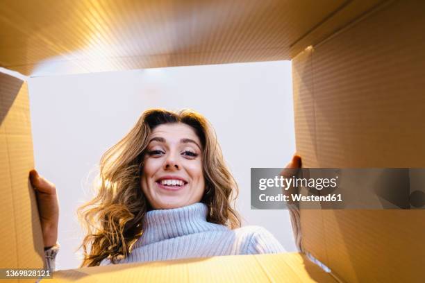 happy woman peeking in box on sunny day - nach oben gucken stock-fotos und bilder