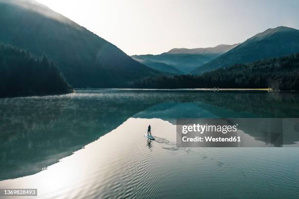 woman paddleboarding on sylvenstein lake, bad tolz, bavaria, germany - paddleboard stock-fotos und bilder