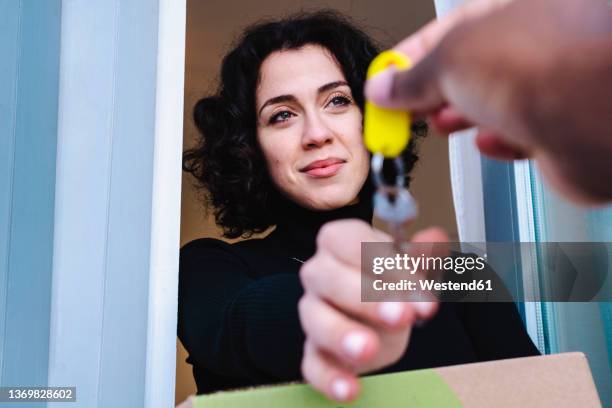 smiling woman taking keys from real estate agent in new house - landlord stock pictures, royalty-free photos & images