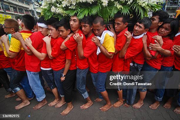 Catholic devotees walk barefoot while carrying a religious image of the Child Jesus to celebrate the grand procession of the feast of Santo Nino...