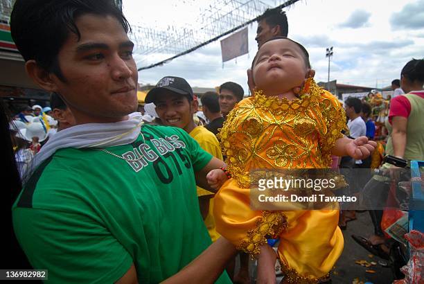 Catholic devotee hoists a month old baby dressed as Santo Nino during the grand procession of the feast of Santo Nino dubbed "Lakbayaw" from the...