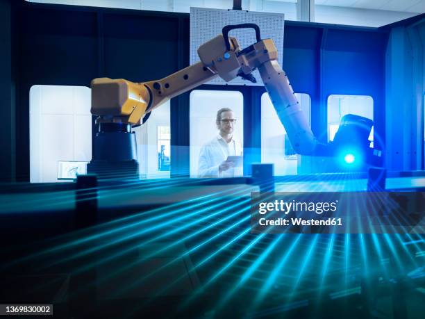 engineer examining surveying robot through glass window in industry - robotic arm factory stock pictures, royalty-free photos & images