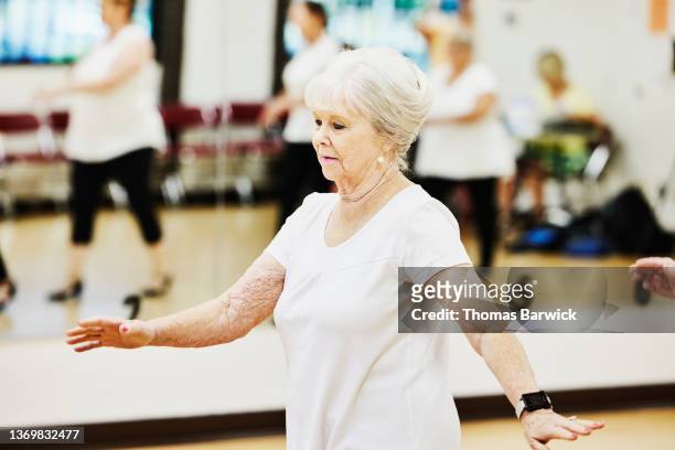 Medium wide shot of senior woman in tap dance class at retirement community center