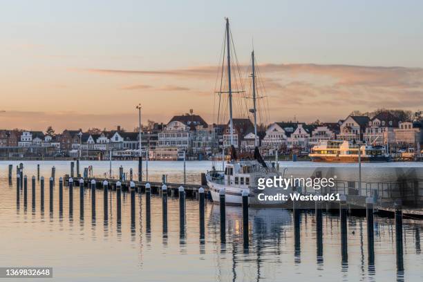 germany, schleswig-holstein, lubeck, yacht moored in harbor at dusk - travemünde stock pictures, royalty-free photos & images