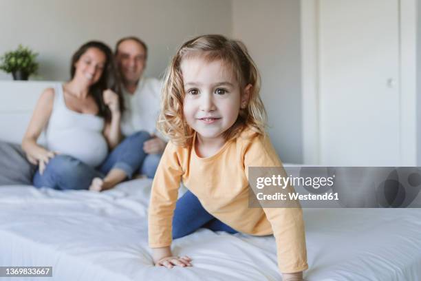 cute blond girl with mother and father on bed at home - 2 year old blonde girl father stock pictures, royalty-free photos & images