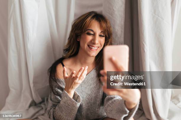 happy woman doing video call on smart phone in front of backdrop - bangs stock-fotos und bilder