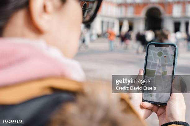 woman using mobile phone gps navigation map while having a walk outdoors on the street. technology and geolocation concept. - gps stock-fotos und bilder