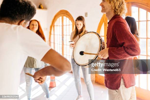 mature man playing drum by friends in music classroom - percussion instrument stock pictures, royalty-free photos & images